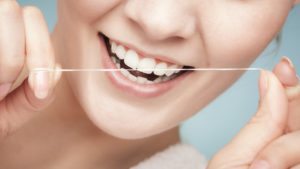  girl cleaning her white teeth with dental floss Daily health care. Studio shot.
